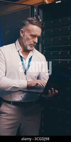 Laptop, typing and technician or man in server room for cyber security, software update and database system. Programmer, developer and cybersecurity Stock Photo