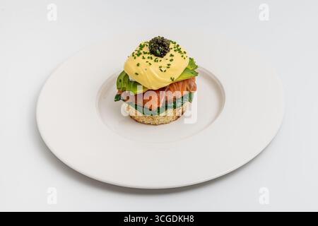 Gourmet eggs benedict with smoked salmon and caviar on white plate Stock Photo