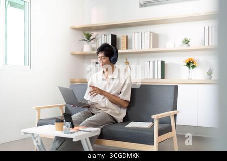 Remote Work. Young man engaged in online meeting with laptop in modern home office. Stock Photo