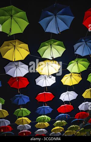 Many Illuminated Colorful Umbrellas Hanging Against Sky at Night in Switzerland Stock Photo