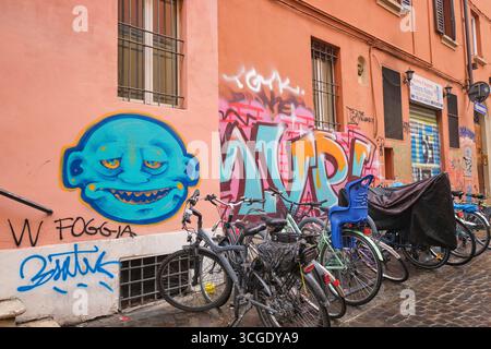 Typical view of a wall near a bicycle rack, covered in spray paint images. Street art, graffiti in Bologna, Italy. Stock Photo