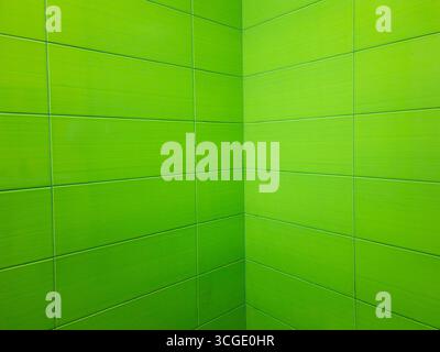 Green rectangular ceramic tiles creating a vibrant and modern look, covering the corner of a bathroom wall, providing a clean and waterproof surface Stock Photo