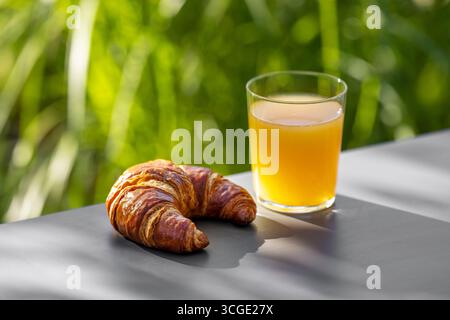 glass of orange juice and croissant on sunny table, selective focus Stock Photo