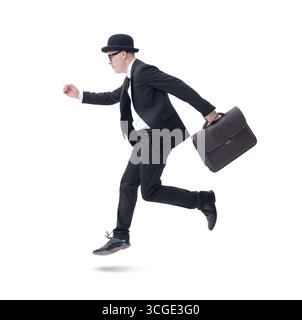 Businessman with bowler hat and briefcase running to an appointment, isolated on white background. Stock Photo