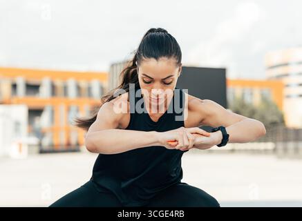 Young fit woman exercising outdoors. Sportswoman in fitness attire doing warm-up exercises. Stock Photo