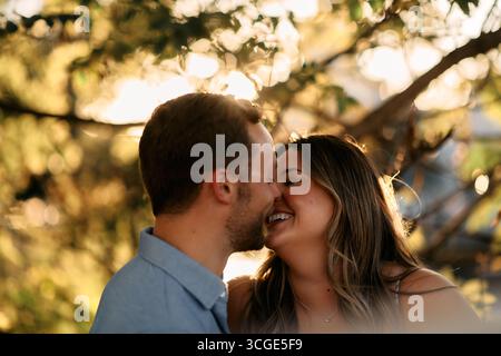 Young couple sharing a romantic kiss outdoors in warm evening
