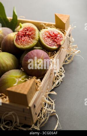 Fresh figs placed into wooden box on dark table. Stock Photo