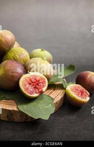 Fresh figs placed on wooden cutting board on dark table. Stock Photo