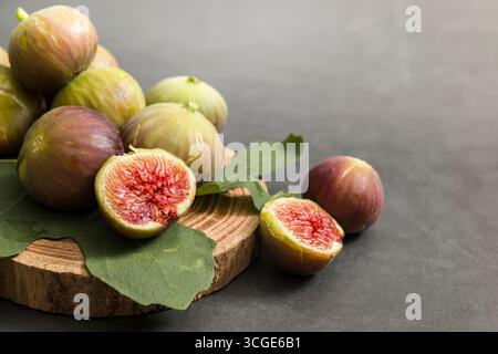 Fresh figs placed on wooden cutting board on dark table. Stock Photo