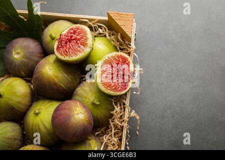 Fresh figs placed into wooden box on dark table. Stock Photo