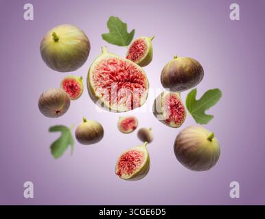 Fresh ripe figs whole and sliced with leaves falling on violet background. Stock Photo