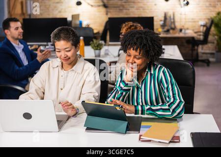 Multi ethnic team collaborating on project using laptop and tablet in office Stock Photo