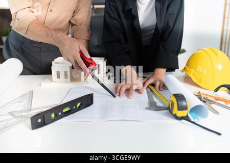 Construction Collaboration. Architects reviewing blueprints together at a modern workspace. Stock Photo