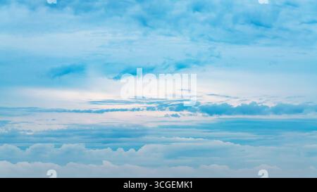 Soft blue sky filled with layered cumulus and cirrostratus clouds. Stock Photo