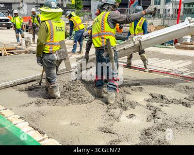 Denver, Colorado, USA - 4 June 2025: Construction workers laying concrete on a new roadway in downtown Denver Stock Photo