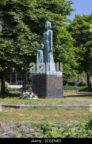 A statue of a woman and child stands prominently in a green park Gorinchem, surrounded by trees, symbolizing peace and remembrance. Gorinchem, Netherl Stock Photo