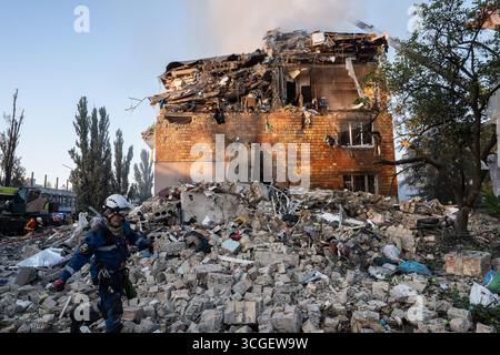 Kyiv, Ukraine. 28th Aug, 2025. A member of the Ukrainian emergency services is seen at the site of an overnight air strike on civilian apartment building. Emergency crews are seen extinguishing fires, searching for survivors beneath the rubble, and assessing the destruction. Scenes show bloodstains on the ground and personal belongings scattered amid the debris. At least 15 people were killed in the Russian airstrikes, and the death toll may rise, though the exact number has not yet been confirmed. (Photo by Patryk Jaracz/SOPA Images/Sipa USA) Credit: Sipa USA/Alamy Live News Stock Photo