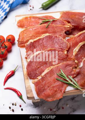 Jerky pork meat on wooden tray and various spices on table Stock Photo