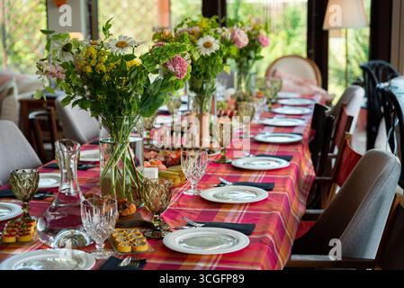 A beautifully arranged dining table showcases vibrant floral centerpieces and fine glassware, creating a warm and inviting atmosphere perfect for gath Stock Photo