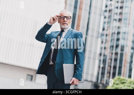 Confident male professional dressed in a sharp suit walking outdoors near modern office buildings Stock Photo