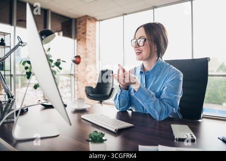 Young businesswoman in a modern office engaging in a professional online chat with enthusiasm and expertise Stock Photo