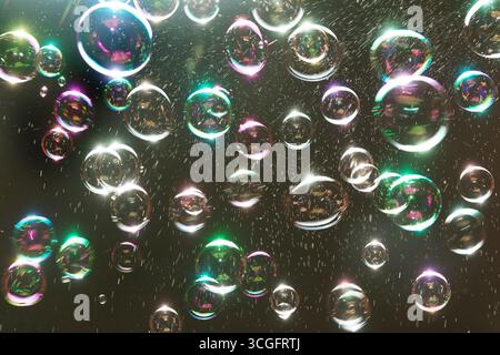 Bubbles floating against a black background, with rainbow colours Stock Photo