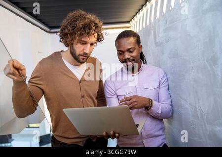 Team collaboration and digital transformation with colleagues sharing ideas at a laptop in office Stock Photo