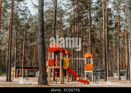 Empty playground with multi-colored play complex in pine forest, panorama on summer cloudy day Stock Photo