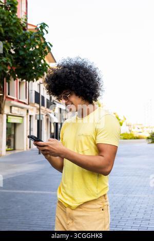 Young man using smartphone walking down the street Stock Photo