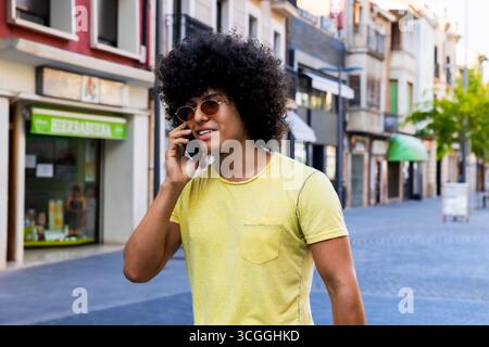 Young man walking down the street talking on smartphone Stock Photo