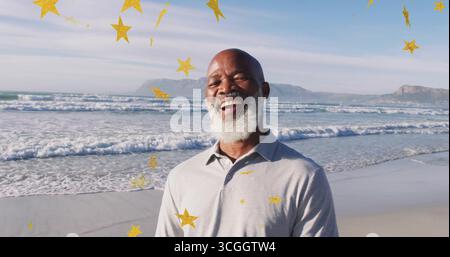 Smiling African American man in light grey shirt on beach, waves rolling under golden star overlays Stock Photo