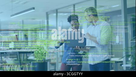 Reviewing code, professionals viewing laptop with green code overlay in office with monitors Stock Photo