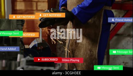 Grinding workpiece with angle grinder by worker in coveralls and apron in workshop, sparks flying Stock Photo