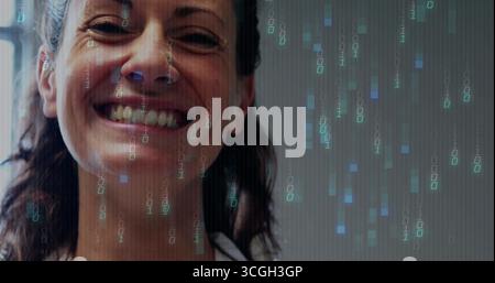 Smiling mid adult woman wearing white top displaying binary overlay in studio, with code streams Stock Photo