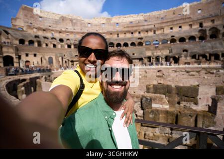 Happy diverse couple taking selfie at the Colosseum in Rome Stock Photo