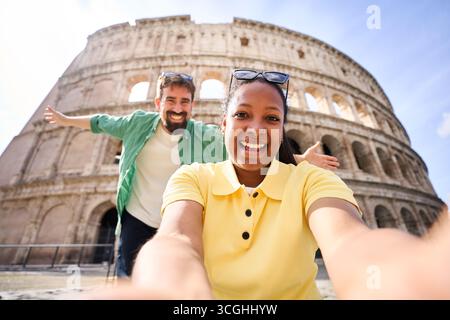 Happy couple on holidays together, taking a cheerful selfie with the colosseum in Rome. Stock Photo