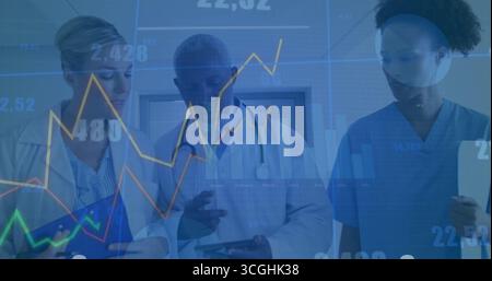 Analyzing medical team wearing coats, scrubs tapping tablets in clinic hallway, displaying charts Stock Photo