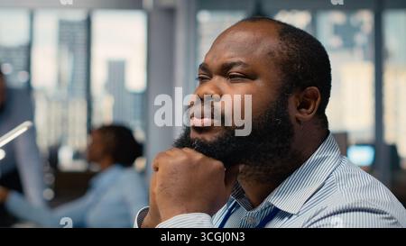 Close up of trader daydreaming, visualizing becoming rich after stock market speculations. African american man in prop firm office lost in thought, picturing prosperous trade Stock Photo