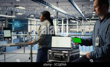 Data center worker uses isolated screen smartphone while deploying deep learning software. Server hub employee uses chroma key mobile phone while training AI systems with datasets, camera A Stock Photo