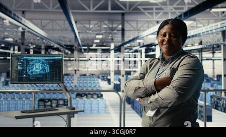 Portrait of smiling IT professional in server farm optimizing machine learning systems handling tasks. Happy data center female engineer adjusting neural networks AI model parameters, camera A Stock Photo