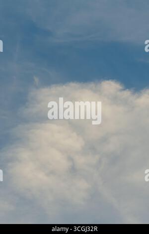 Soft white cumulus clouds blend seamlessly into wispy cirrus formations, drifting across a blue sky. Stock Photo