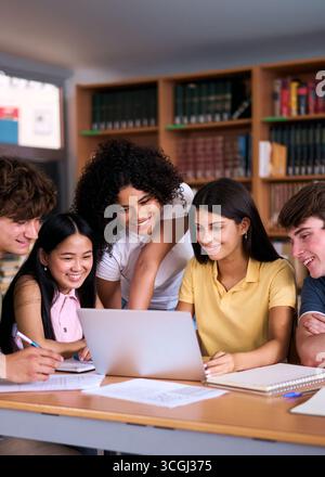 High school students collaborating on project in library using laptop Stock Photo