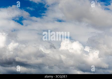 Cumulus clouds with patches of blue sky and areas of gray overcast. Cumulus clouds are fluffy, cotton-like clouds with bright tops and darker bases. Stock Photo