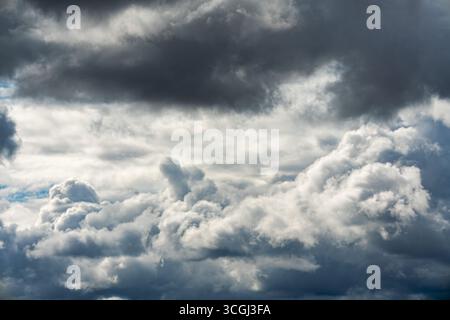 Dark storm clouds and cumulus formations filling the sky, with areas of light and shadow. Stock Photo