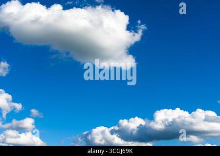 Minimalist scene of white fluffy clouds against a deep blue sky, capturing the beauty and tranquility of nature. Stock Photo