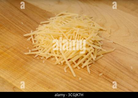 Pile of Grated Parmesan Cheese on Wooden Cutting Board Stock Photo