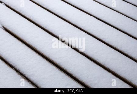 Close up abstract texture background of a fine layer of fresh white snow on a wooden deck surface Stock Photo