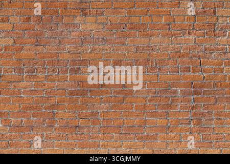 Abstract texture background of a weathered exterior vintage orange color brick wall surface, with beige limestone foundation at bottom Stock Photo