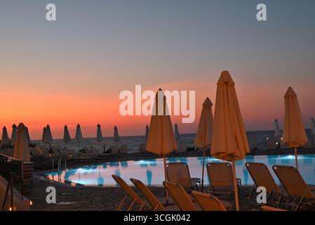 Pool with parasols at sunset in Sissi, Crete, Greece Stock Photo