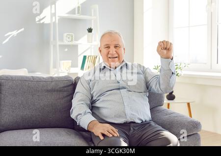 Portrait of optimistic handsome senior confident happy mature man sitting on sofa looking at camera  Stock Photo